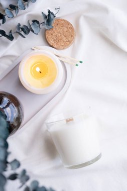 Beyaz kavanozda soya aromalı mum ve okaliptüs yaprakları. Mum modelleme tasarımı. Doğal olarak balmumu mumunu taklit et..