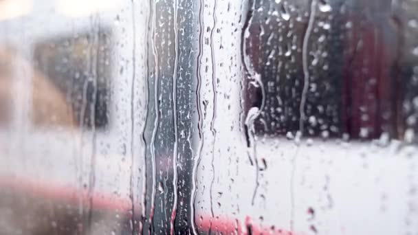 Zbliżenie Ujęcie Szklanego Okna Pokrytego Kroplami Deszczu Rozmazanym Tle Pociągu — Wideo stockowe