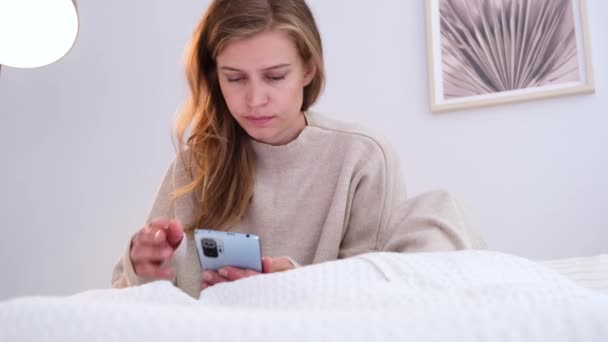 女人坐在床上在家 吃早餐 用智能手机 年轻的千禧年女子在卧室做晨间例行公事 — 图库视频影像