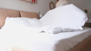 Kafkasyalı kadın sabahları yatağını yapıyor. Genç milenyum kadını yatak odasında sabah rutinini yapıyor.