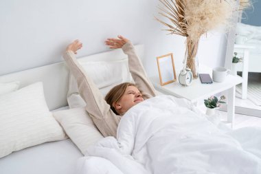 Kafkasyalı kadın sabahları yatağında uyanıyor. Genç milenyum kadını yatak odasında sabah rutinini yapıyor.