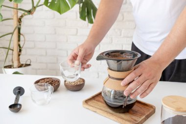 Adam ev mutfağında kahve hazırlıyor.