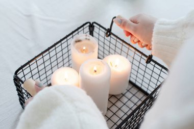 Merry Christmas and Happy New Year. Woman in warm white winter sweater standing at the kitchen at home lighting up the candles