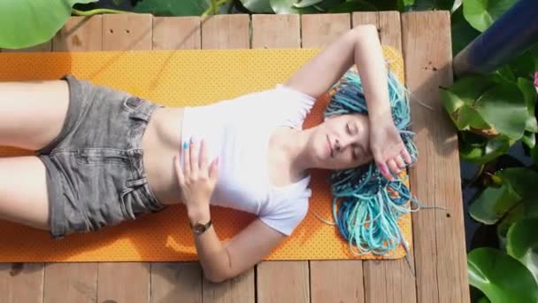 在荷花湖畔的瑜伽垫上 躺着美丽的蓝发女子 — 图库视频影像