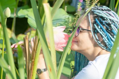 Mavi afro kilitleri olan genç ve güzel bir kadın. Tahta bir delikten Lotus Gölü 'nde dinleniyor. Doğanın tadını çıkarıyor.