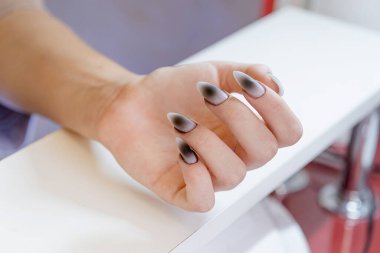 Güzellik salonunda kadın müşterilere manikür yapan tanınmayan bir manikürcü.