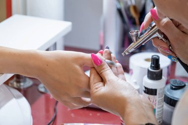 Closeup çekim bir güzellik ile airbrush tarafından bir manikür alma bir tırnak salonu içinde bir kadın. Kadın Başlarken tırnak manikür.