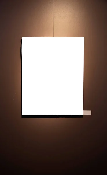 ギャラリーの輝くランプが付いている茶色の壁のブランクの映像フレーム モックアップ — ストック写真