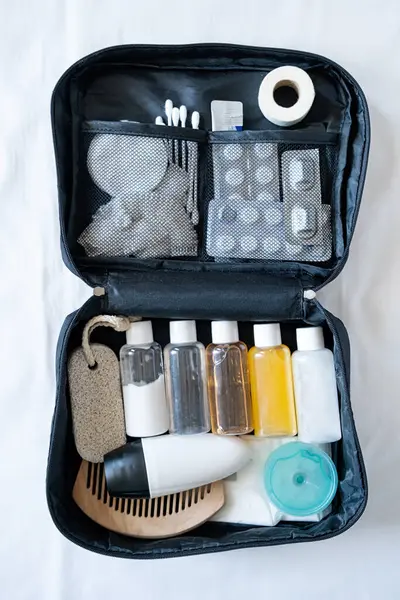 Travel cosmetics kit with bottles, pills and cosmetics on bed , top view