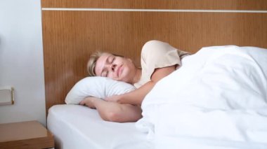 Genç bir kadın uyanıyor ve sabah otel odasında geriniyor.