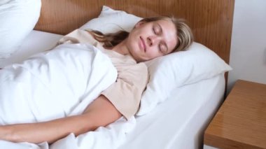 Genç bir kadın uyanıyor ve sabah otel odasında geriniyor.