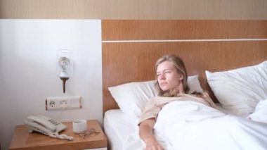 Genç bir kadın uyanıyor ve sabah otel odasında geriniyor.