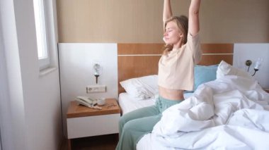 Genç bir kadın uyanıyor ve sabah otel odasında geriniyor.