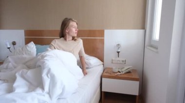 Genç bir kadın uyanıyor ve sabah otel odasında geriniyor.