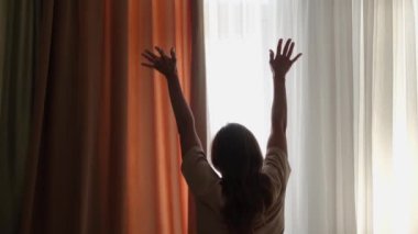 Genç bir kadın uyanıyor ve sabah otel odasında geriniyor.