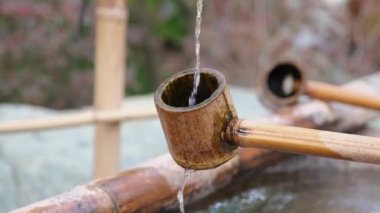 Japonya 'da arınma çeşmesini bambu ve ahşap kepçeyle yakından çek.