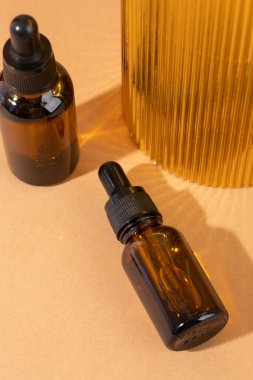 Kahverengi arka planda kehribar cam damlası şişesi, taşlar ve doğal kozmetik bileşimi.