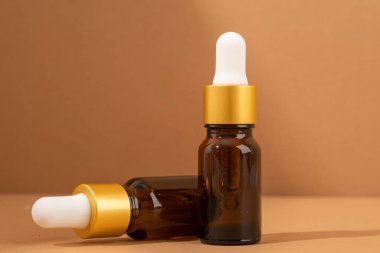 Kahverengi arka planda kehribar cam damlatan şişelerin maketi, minimal.