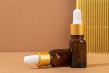 Kahverengi arka planda kehribar cam damlatan şişelerin maketi, minimal.