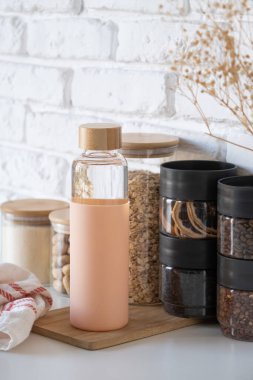 Kurutulmuş yiyecekleri depolamak için cam kavanozları yeniden kullanmak sürdürülebilir yaşam tarzı. İçmek için su dolu cam şişe.