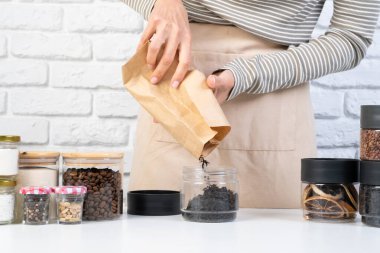 Kadın kurutulmuş yiyecekleri depolamak için cam kavanozları yeniden kullanıyor sürdürülebilir yaşam tarzı evde, boşluğu kopyala