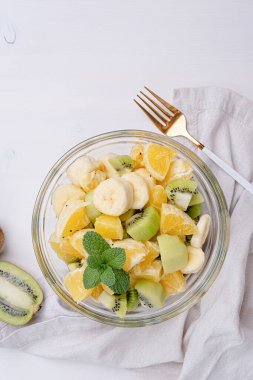 Tabak Beyaz ahşap zemin üzerinde sağlıklı taze meyve salatası. Üstten Görünüm.