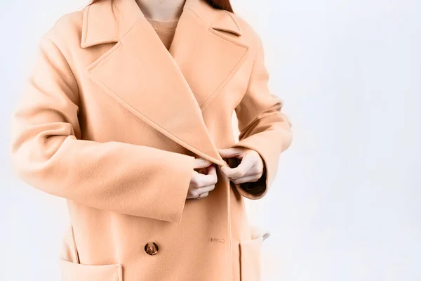 2024年的颜色 Peach Fuzz 穿着米色外套的特写女人选择白色背景的服装 选择衣橱 造型师 购物者 图库照片