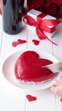 Tanınmayan bir kadın jöleli kalp kesiyor. Sevgililer günü pastası, beyaz ahşap masa.