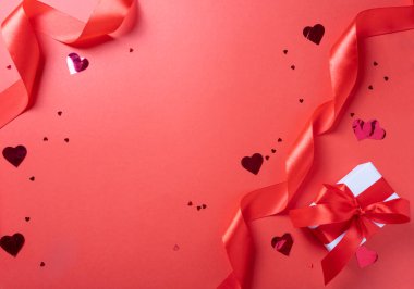 Sevgililer Günü. Kırmızı arka planda sevgililer günü kırmızı kurdeleleri, konfetileri ve hediyeleri.