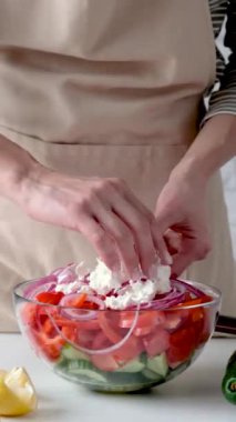 Yunan salatasının pişirme süreci. Kadın elleri sebze doğruyor, zeytin ve yağ ekliyor.