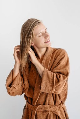 2024 yılının rengi: Şeftali tüyü. Kadın sağlığı. Spa ve sağlık. Banyoya saç maskesi takan mutlu genç bir kadın.