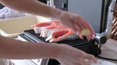 Kadın mutfakta somon bifteği pişiriyor.