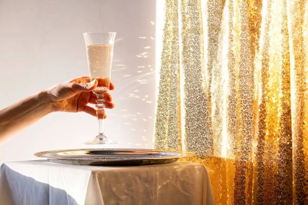 Champagne flute in tray on table against gold sparkling background
