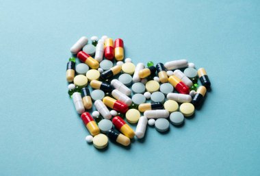 Mavi arka planda kalp şekli oluşturan haplar, boşluğu kopyala