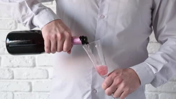 Человек Открывающий Бутылку Розового Шампанского Белый Кирпичный Фон Стены — стоковое видео