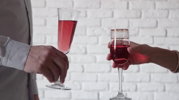 酒精饮料概念 无法辨认的男女举着红色的香槟 白色的砖墙背景敬酒 — 图库视频影像