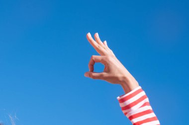 Kadın eli, arka plandaki parmaklarıyla onay işareti yapıyor. Fotokopi alanı olan güzel kadın elleri. Sevgililer gününde aşk konsepti.