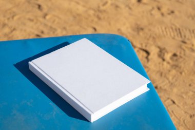 Kitap tasarımı. Tatilde kitap okumak. Kumsalda boş bir kitap maketi.