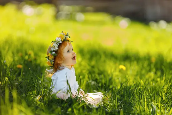 Şirin küçük kız açık havada güzel bir bahar çelengi giyiyor, mesaj için yer var. Kızıl saçlı bebek doğada vakit geçiriyor. 