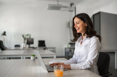 Young cheerful and attractive employee typing on her computer clipart