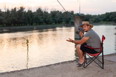 Young fisherman with straw hat pulling river weed with his fishing gear clipart