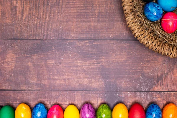round easter basket with colorful easter eggs on rustic white wooden tabletop