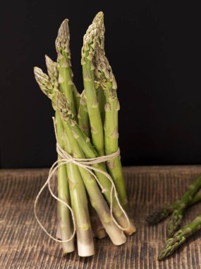 Eski ahşap tahtanın üzerinde duran bir avuç taze yeşil kuşkonmaz.