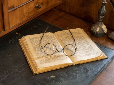 Eski Alman yazıları, yuvarlak okuma gözlükleri ve antika sekreterin şamdanı ile dolu bir hayat.