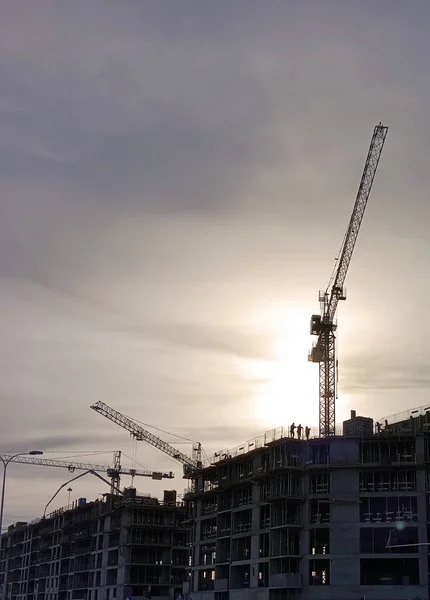 Cranes at the construction site of a new housing estate, in the late afternoon