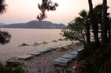 Şemsiyeler ve güneşlikler gün batımında Marmaris sahilinde.                                     