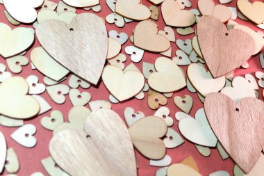 Koyu pembe arka planda, biraz daha küçük ahşap kalplerden oluşan bir kolleksiyonun üstünde dört tahta kalp.