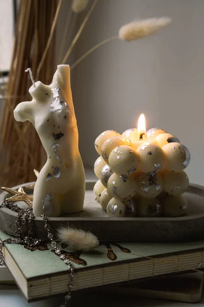 A bubble candle and a white candle shaped as a female body on a concrete tray. High quality photo