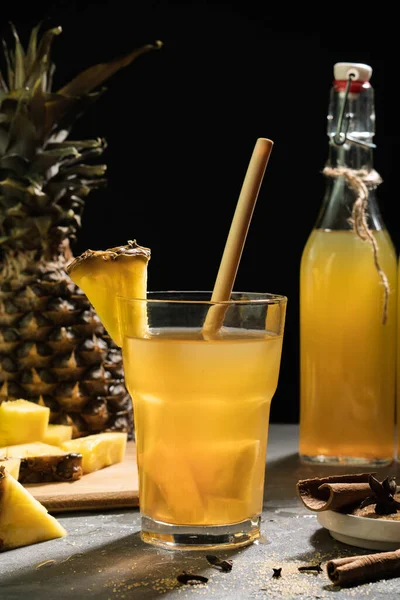 Ananas Tepache. Ferahlatıcı içecek, taze ananas kabuğu ve çekirdekten yapılan hafif mayalanmış içecek, artı kahverengi şeker. Yüksek kalite fotoğraf. Koyu arkaplanda cama servis ediliyor..