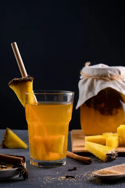 Ananas Tepache. Ferahlatıcı içecek, taze ananas kabuğu ve çekirdekten yapılan hafif mayalanmış içecek, artı kahverengi şeker. Yüksek kalite fotoğraf. Bardakta servis ediliyor. Alçakgönüllülük. Koyu arkaplan.